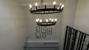 A staircase with a black railing, a wall-mounted fan, and a chandelier with multiple bulbs. - 101 Seoul Hostel (Bangkok)