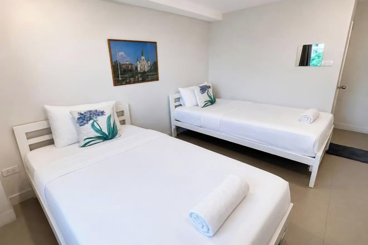 A hotel room with two single beds, a small bedside table, and a wall-mounted picture.