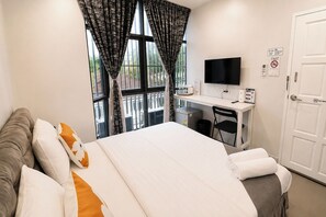 A hotel room with a bed, a desk with a computer, a TV, and a door with a 'No Smoking' sign. - 101 Seoul Hostel (Bangkok)