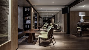 A modern library with rows of bookshelves, comfortable seating, and a flat-screen TV. - Chongqing David‘s Deer Boutique Hotel (Chongqing)