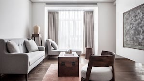 A modern living room with a sofa, armchair, wooden coffee table, and a large abstract painting on the wall. - Chongqing David‘s Deer Boutique Hotel (Chongqing)