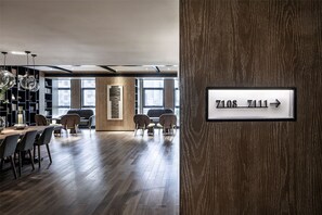 A modern interior with a wooden floor, a dining area with chairs and a table, and a sign indicating room numbers 7108 and 7111. - Chongqing David‘s Deer Boutique Hotel (Chongqing)
