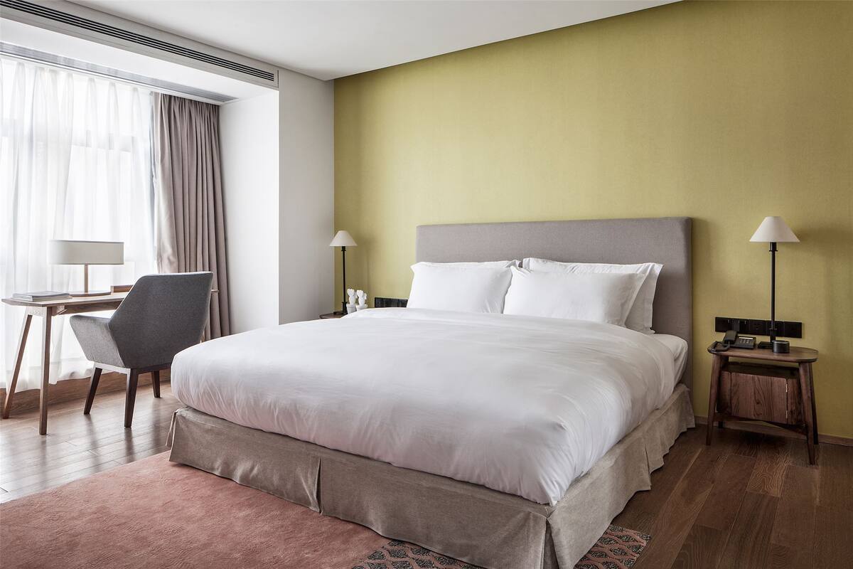 A hotel room with a large bed, a desk, and a chair.