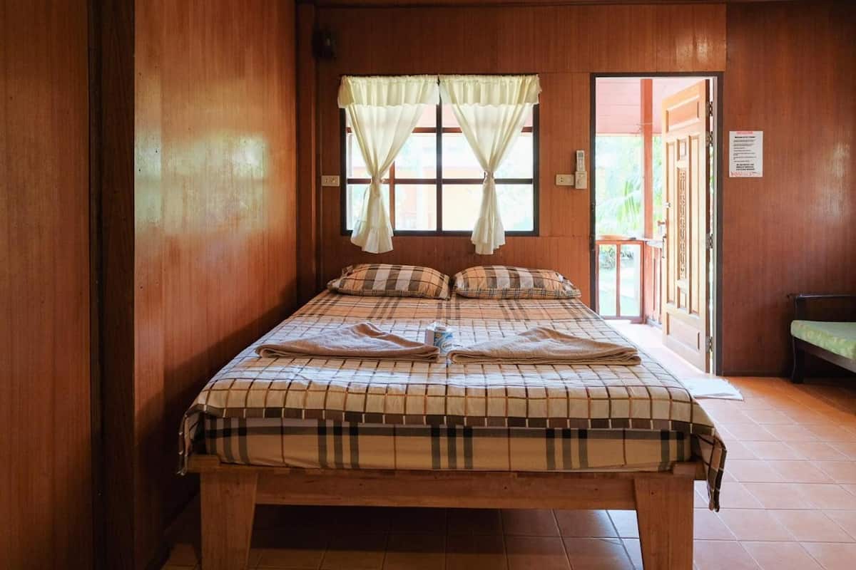 A wooden room with a bed, curtains, and a bench.