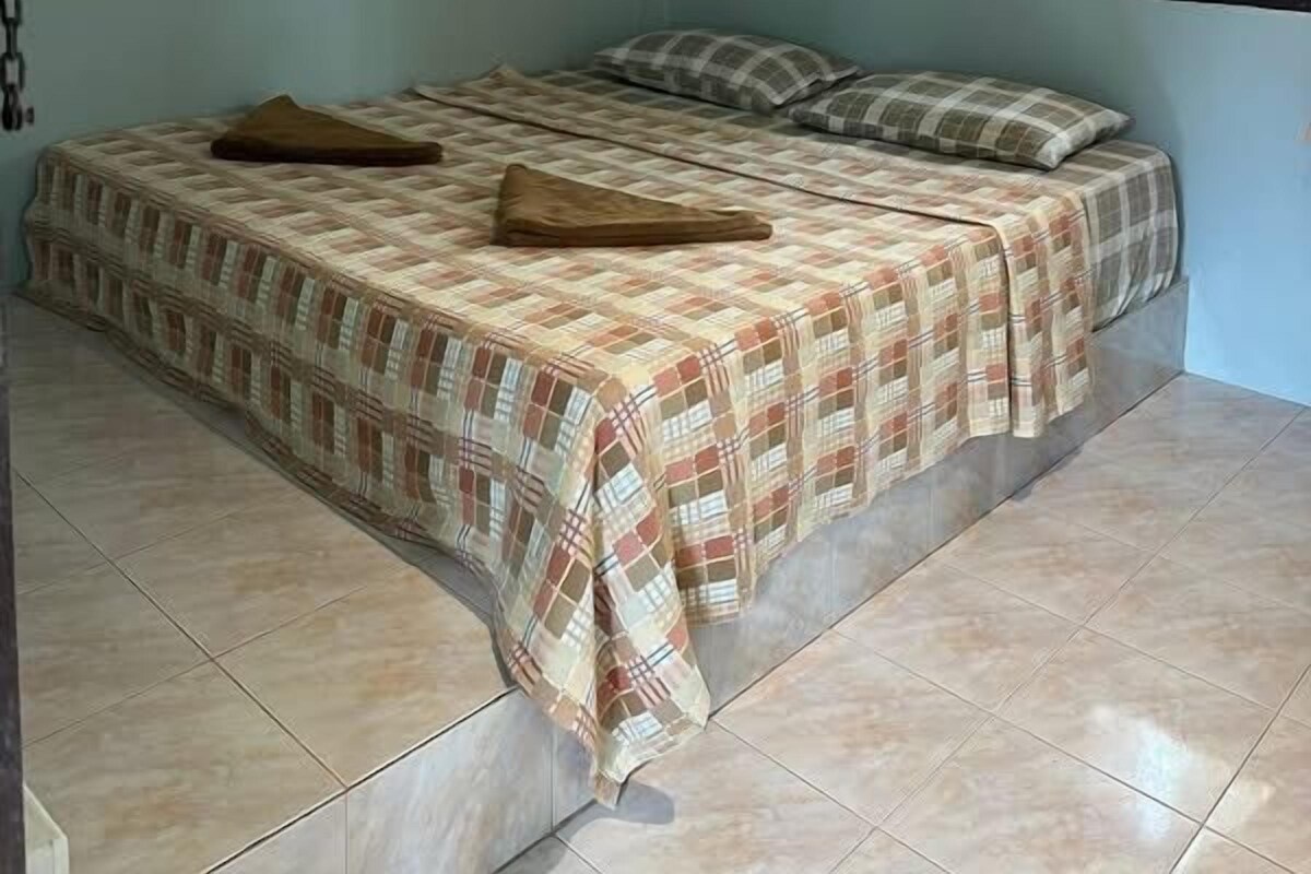 A bedroom with a bed, a window with curtains, and an air conditioning unit.