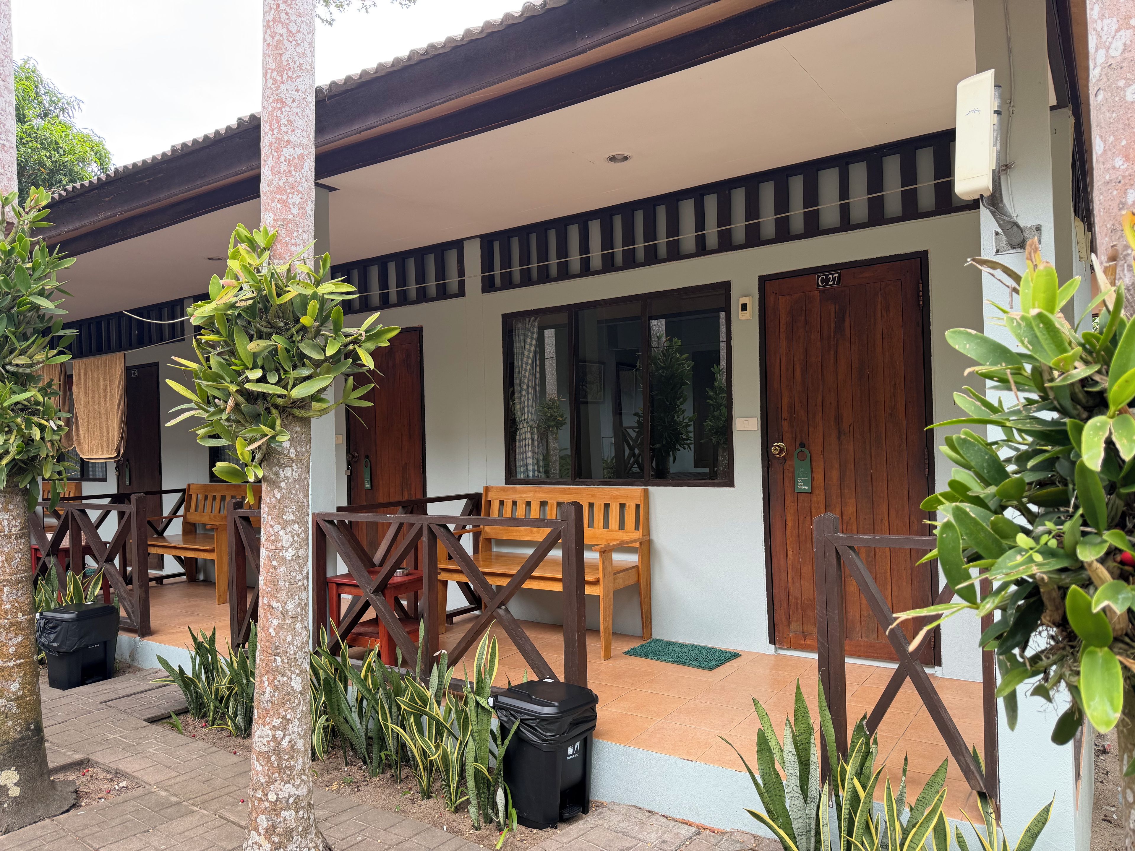 A covered outdoor seating area with wooden furniture and potted plants.