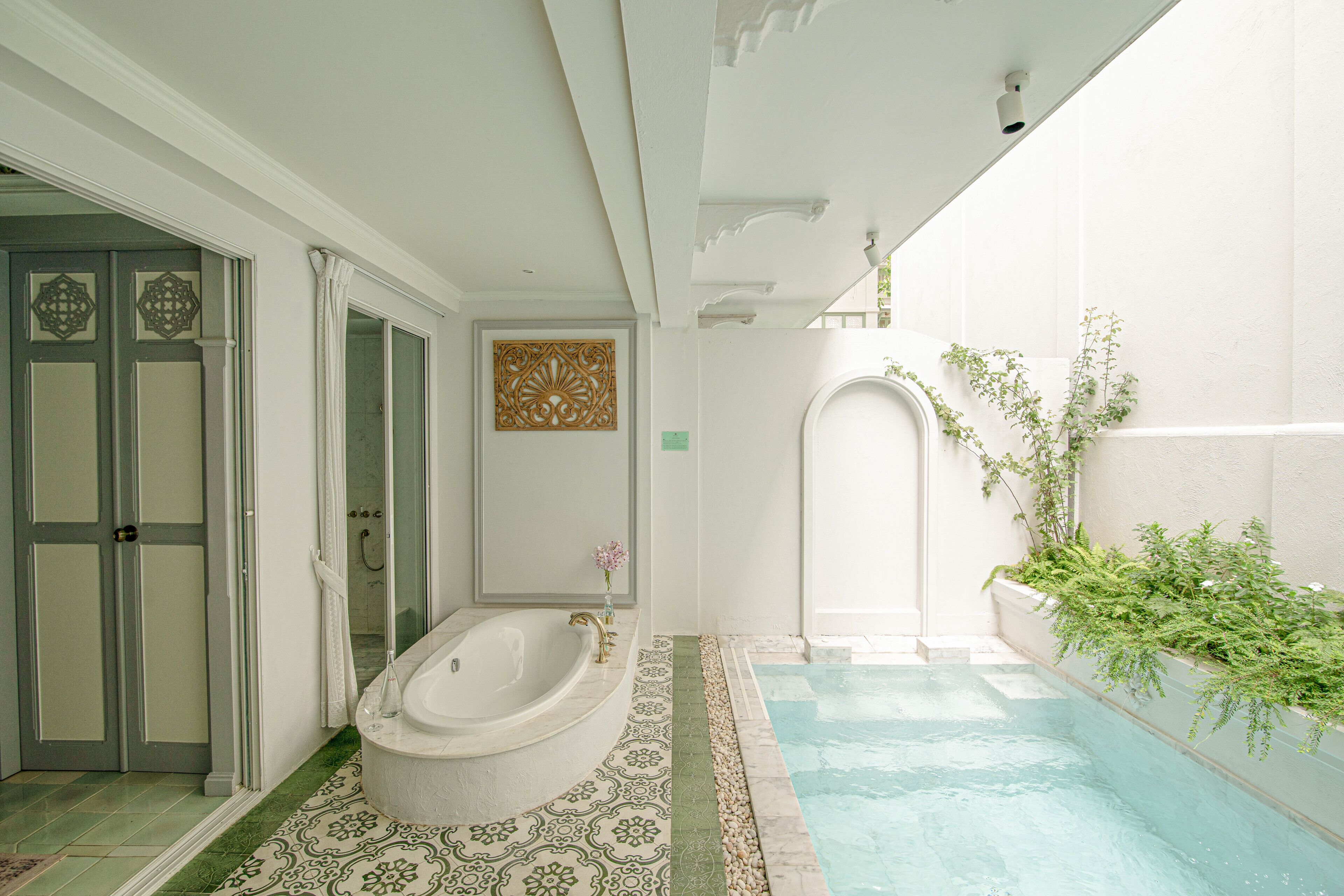 A bathroom with a bathtub, a shower, and a small pool.