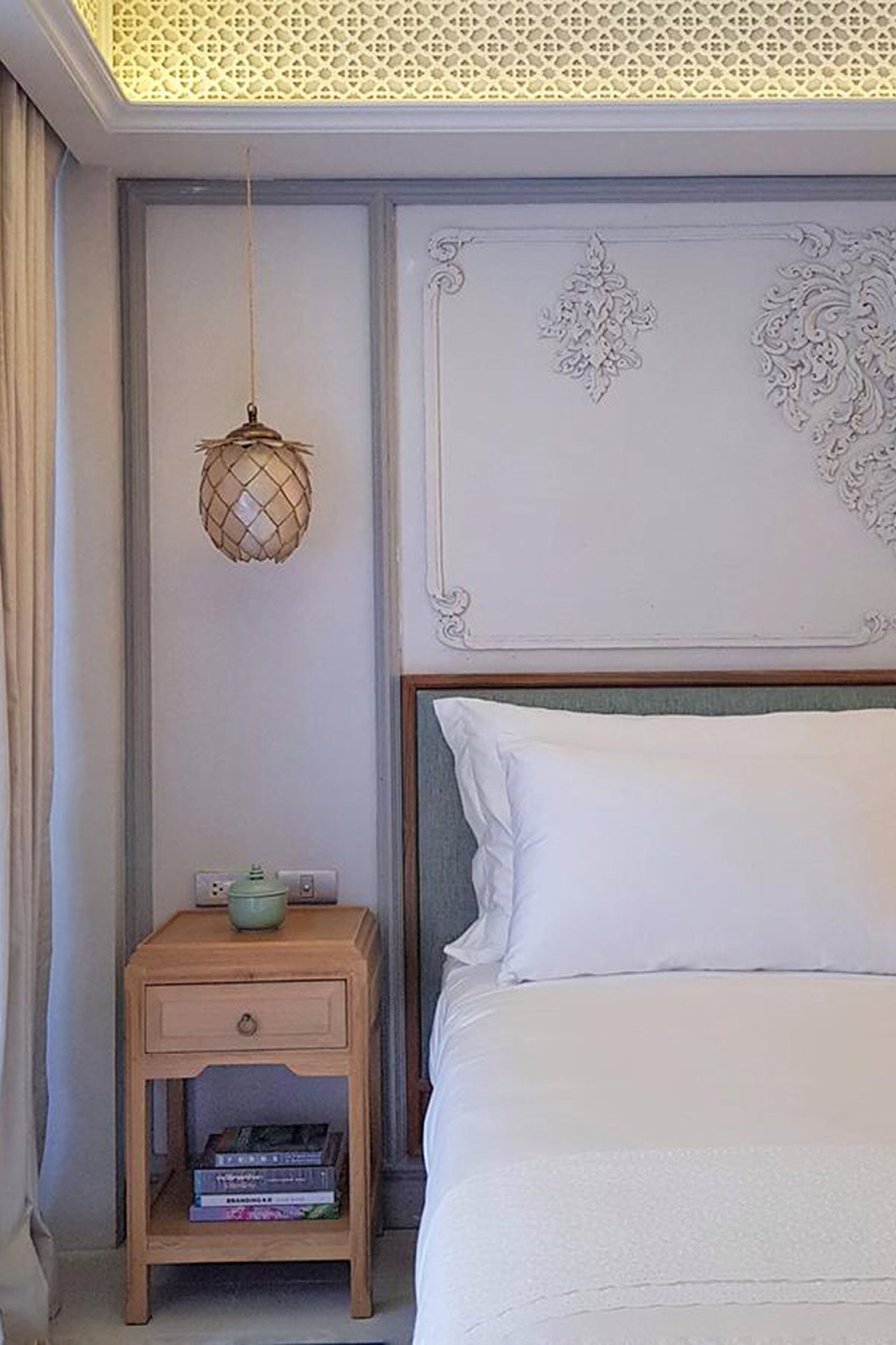 Une chambre à coucher bien aménagée, avec un lit, une table de chevet dotée d’une lampe et un panneau décoratif au mur.