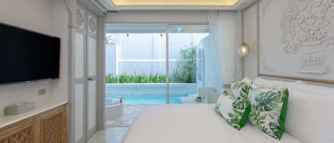 Un dormitorio con una cama grande, un televisor de pantalla plana, un ventilador de techo y vista a una piscina.
