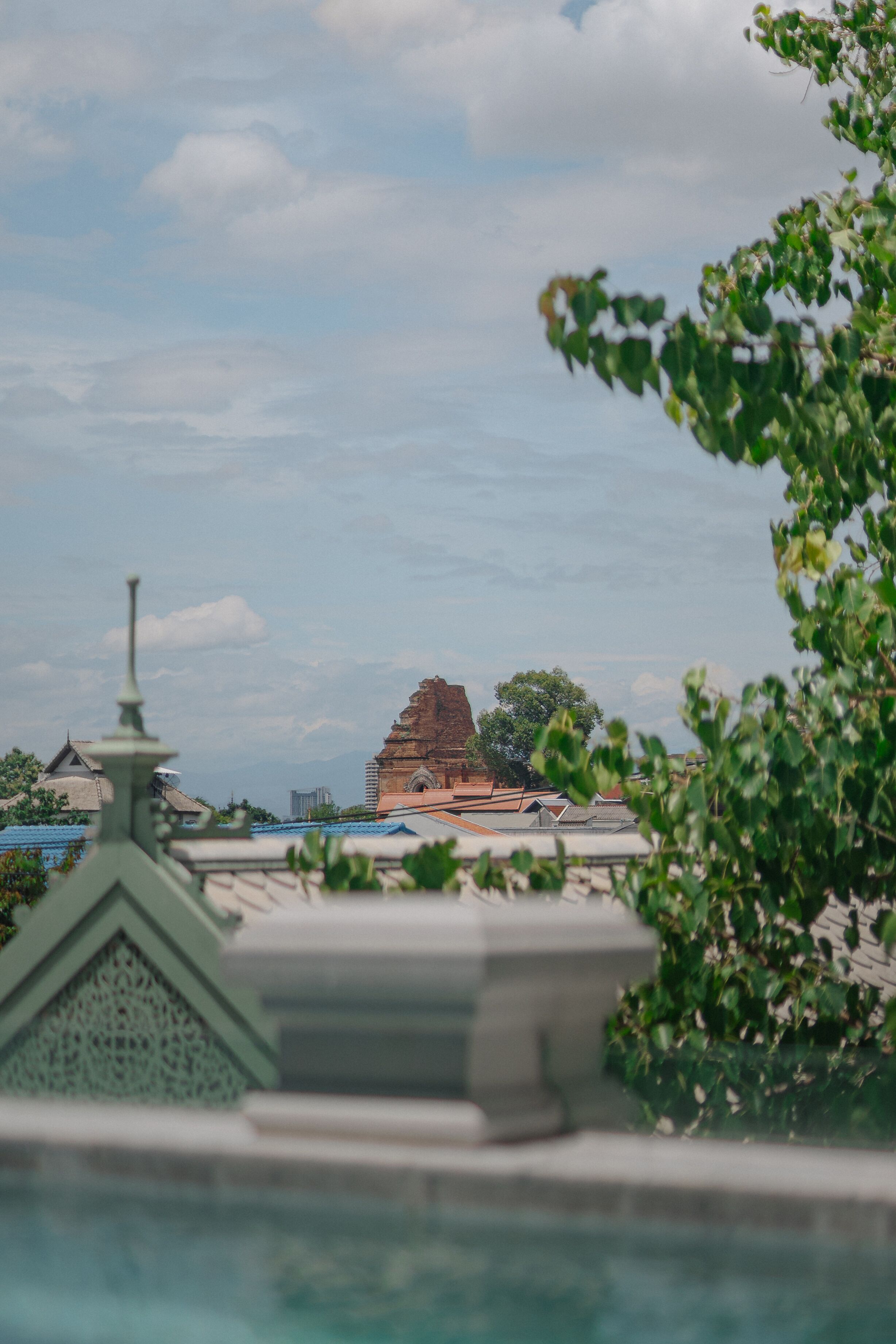 A view of a temple with a traditional structure, surrounded by greenery and modern buildings.