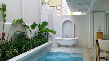 Una pequeña piscina interior con una bañera blanca, rodeada de abundante vegetación.