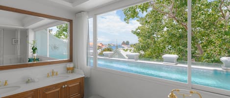 A bathroom with a large window, a bathtub, and a vanity with a mirror.