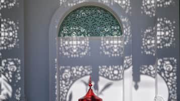 A room with a decorative window, a red object in the foreground, and intricate wall patterns.