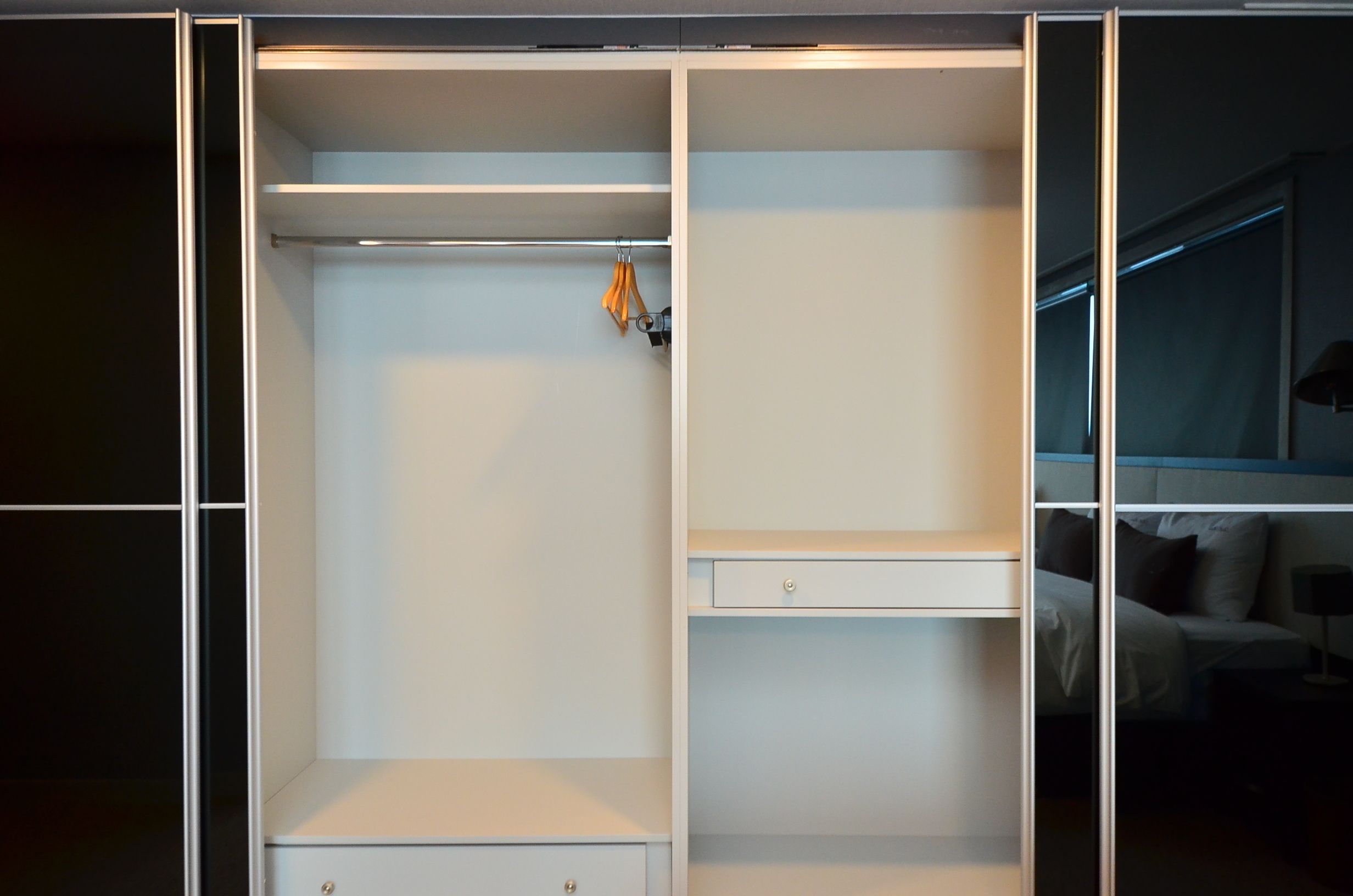 A walk-in closet with open shelves, a hanging rod, and a small drawer unit.
