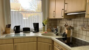 Une cuisine avec des meubles de rangement en bois, un évier, une machine à café et un grille-pain.