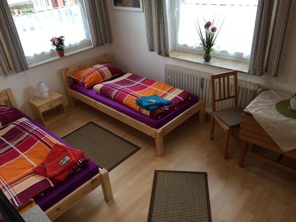 A small, cozy room with two wooden beds, a desk, and a chair. - Abelia Pension & Ferienwohnungen (Helmstedt)