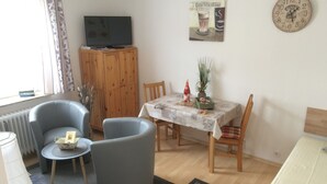 Un salon avec un téléviseur, une table à manger avec des chaises, un canapé et un radiateur.