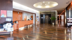 A hotel lobby with a reception desk, a clock, a plant, and a staircase leading to an elevator. - Lakeside Hot Spring Hotel Kunibiki (Izumo)