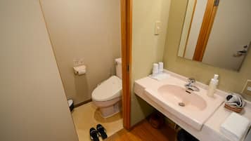 A bathroom with a toilet, sink, and mirror.