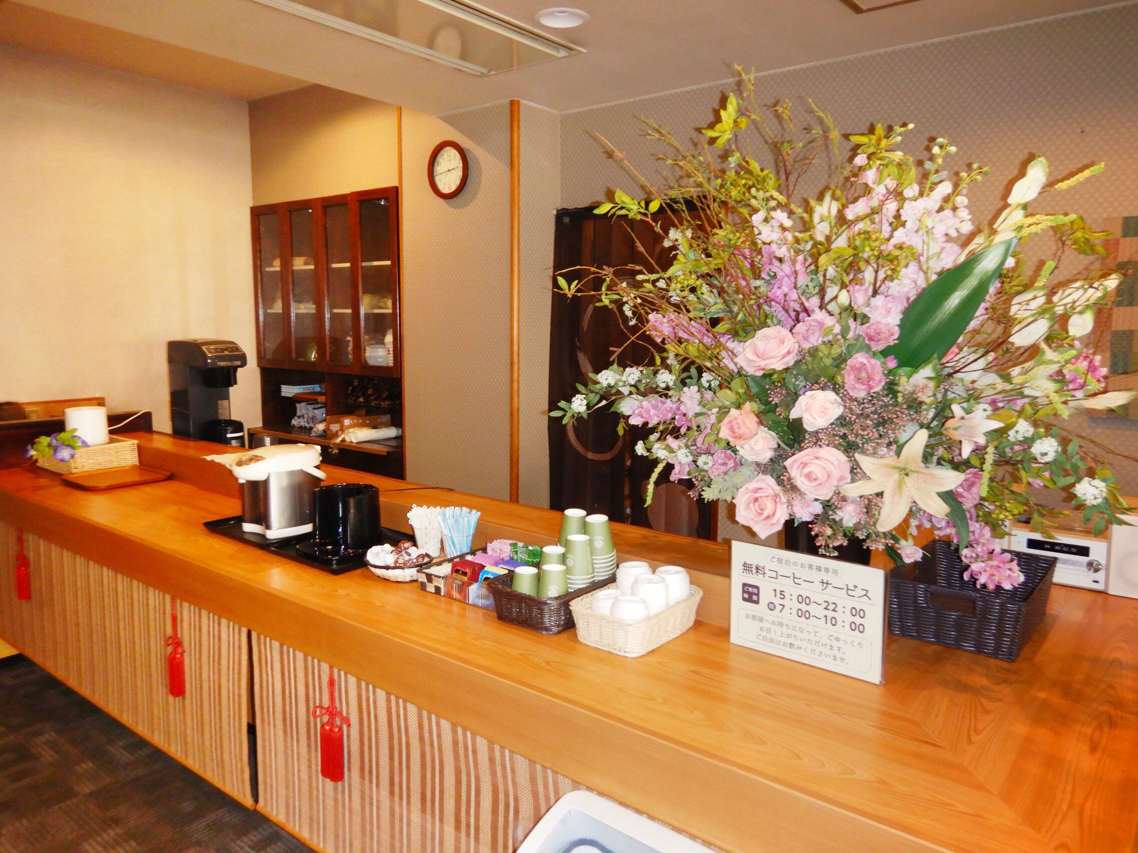 A reception desk with a coffee machine, a clock, and a floral arrangement.