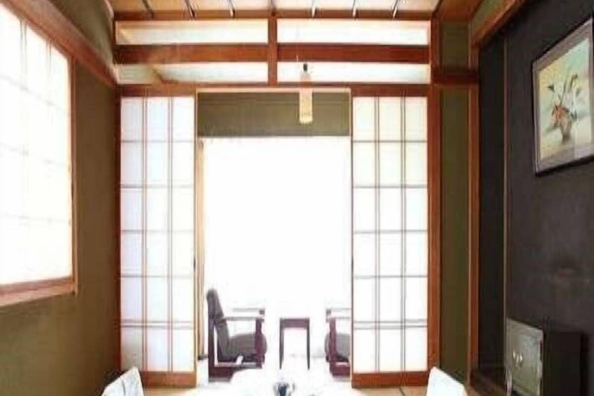 A traditional Japanese room with tatami flooring, a low table with cushions, and sliding doors.