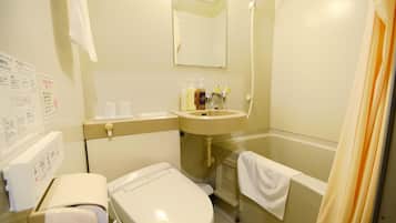 Une petite salle de bain propre, équipée de toilettes, d’un lavabo et d’une douche. On y trouve des articles de toilette sur le comptoir du lavabo.