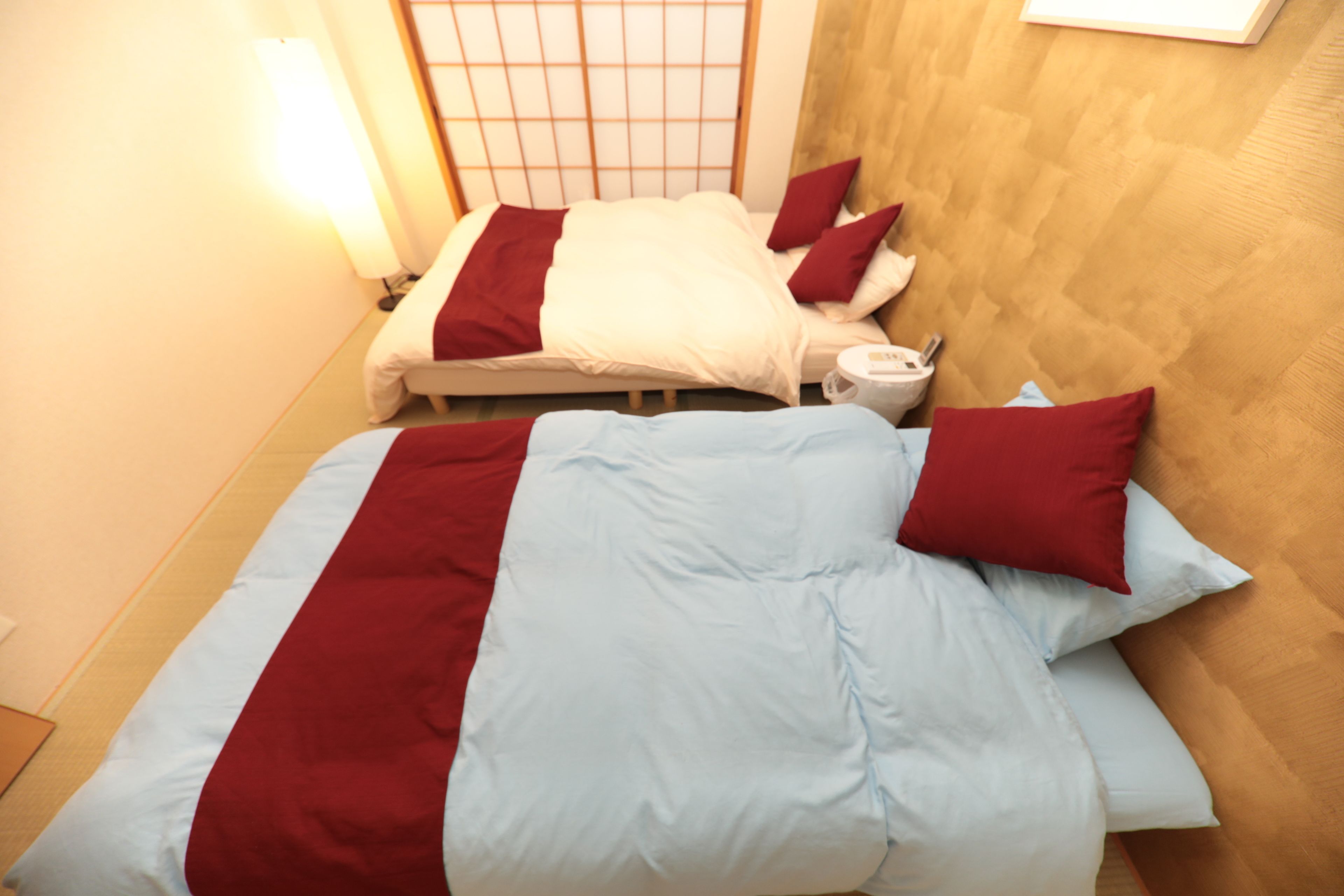 A hotel room with two beds, each with red and white bedding.