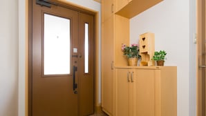 Un pasillo con una puerta marrón, armarios de madera y plantas en macetas.