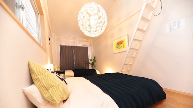 Un dormitorio con cama, ventana, escalera y candelabro.