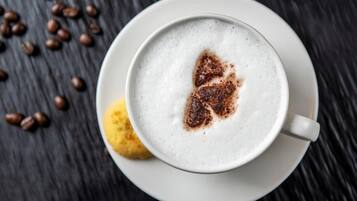 Una tazza di caffè con schiuma e una spolverata di cannella su un piattino bianco.