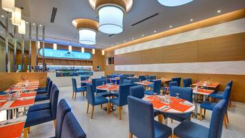 A modern restaurant with blue chairs and tables, a central bar area, and a visible 'Spices' sign.