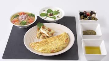 A plate with an omelette, a bowl of soup, and a bowl of yogurt with mint.