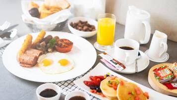 A breakfast setting with a plate of eggs, sausages, and toast, a glass of orange juice, and a cup of coffee.