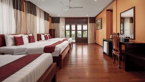 A hotel room with three beds, a desk, a chair, a ceiling fan, and a view of the outdoors. - Lavender Angkor Boutique (Siem Reap)