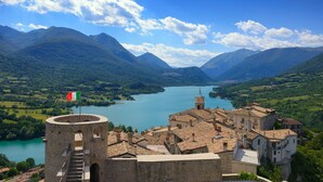 A historic town with a prominent tower, a lake, and surrounding mountains. - Hotel Holidays (Barrea)