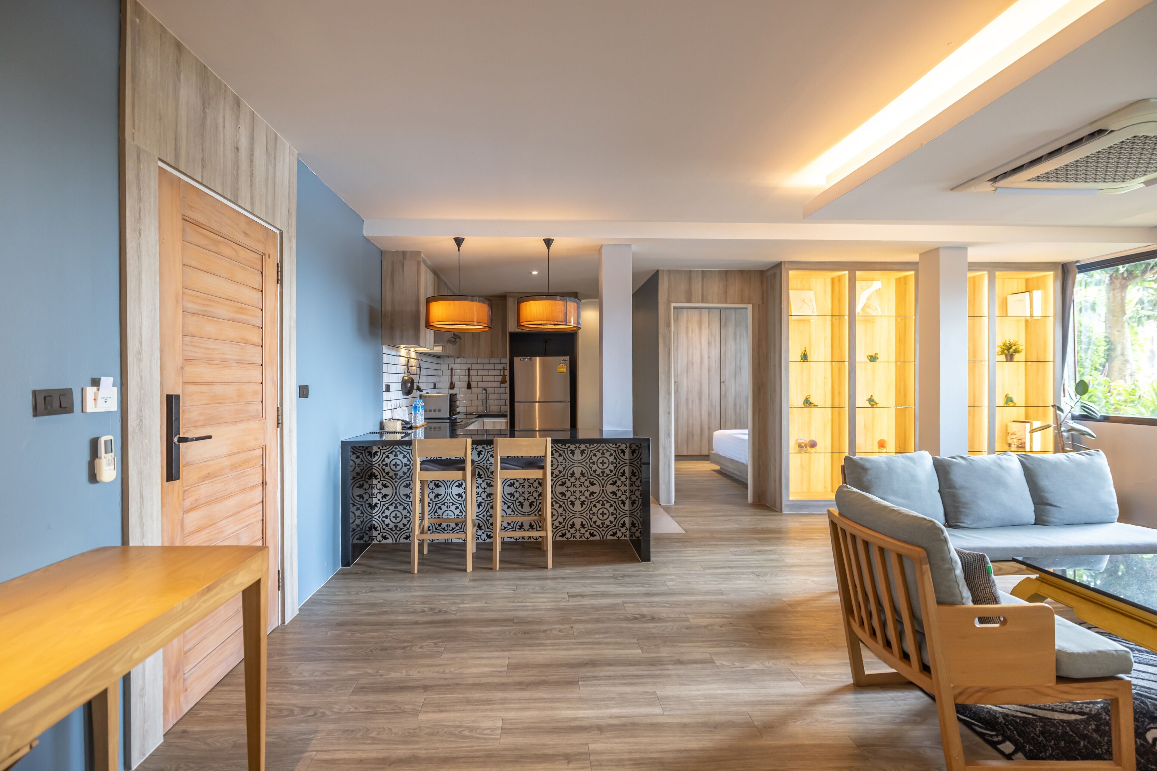 Une cuisine moderne avec un coin repas, un plancher en bois et un canapé avec des coussins.