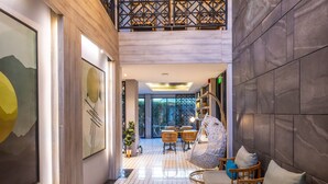 A spacious lobby with a high ceiling, geometric wall panels, a patterned floor, and seating areas. - Antiya Hotel Phuket (Chalong)