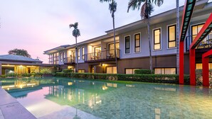 A modern hotel with a swimming pool, multiple balconies, and a well-maintained garden. - Antiya Hotel Phuket (Chalong)