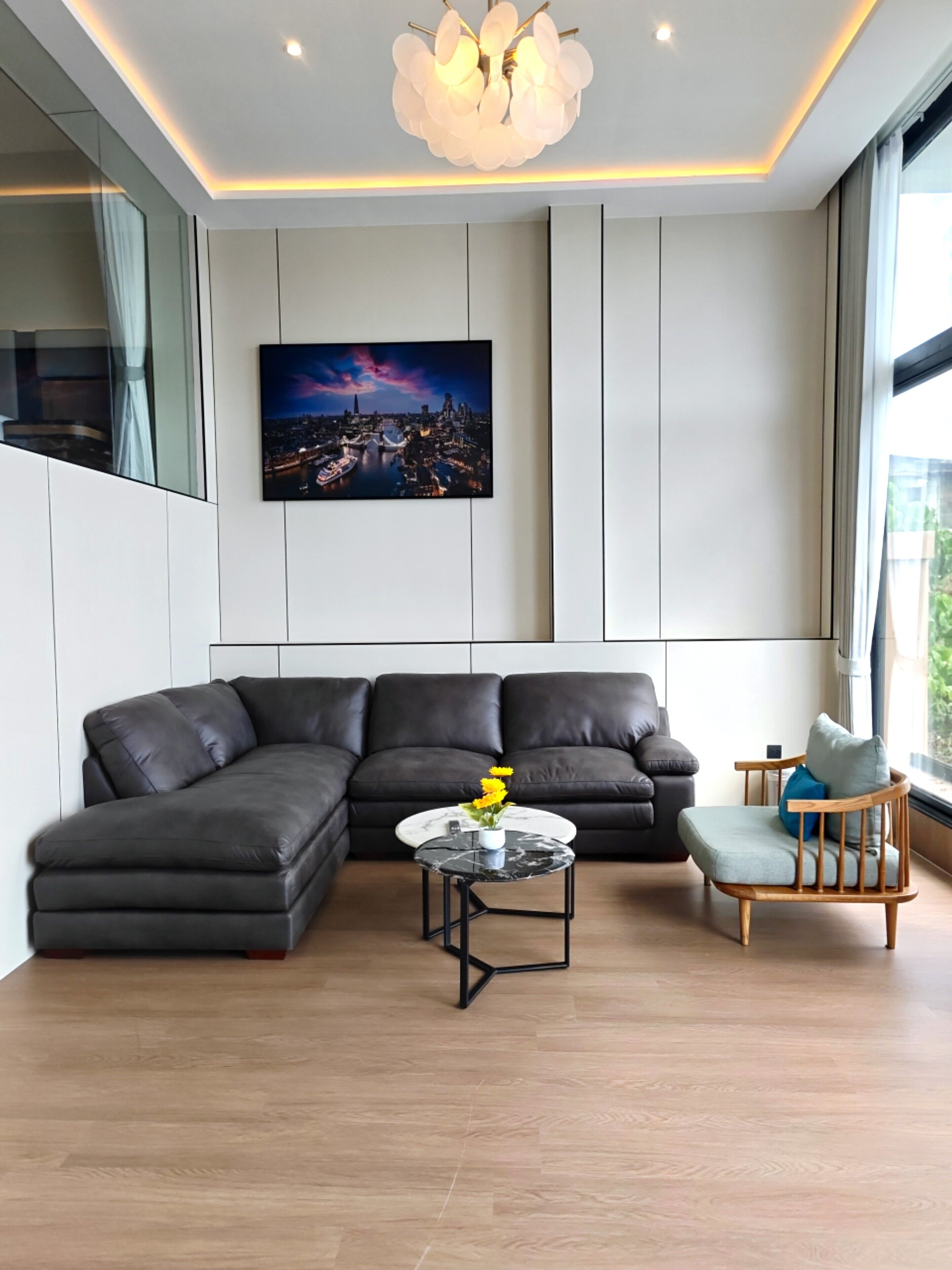 A modern living room with a sectional sofa, a round coffee table, and a wooden chair.
