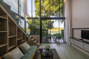 Una sala de estar moderna con una escalera, un sofá, una mesa de centro con flores y un televisor.