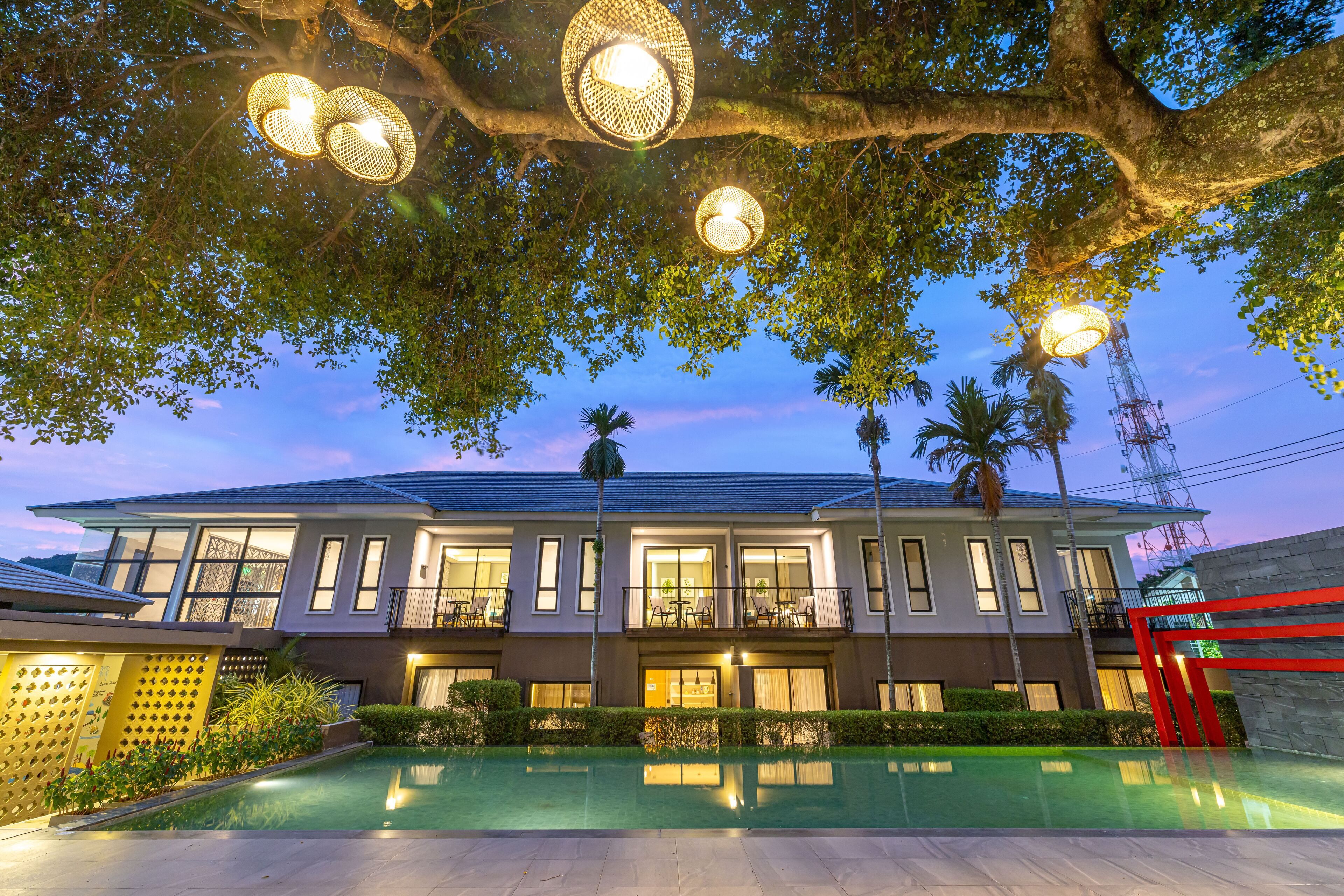 Un edificio moderno de dos pisos con piscina, ventanas amplias e iluminación exterior.