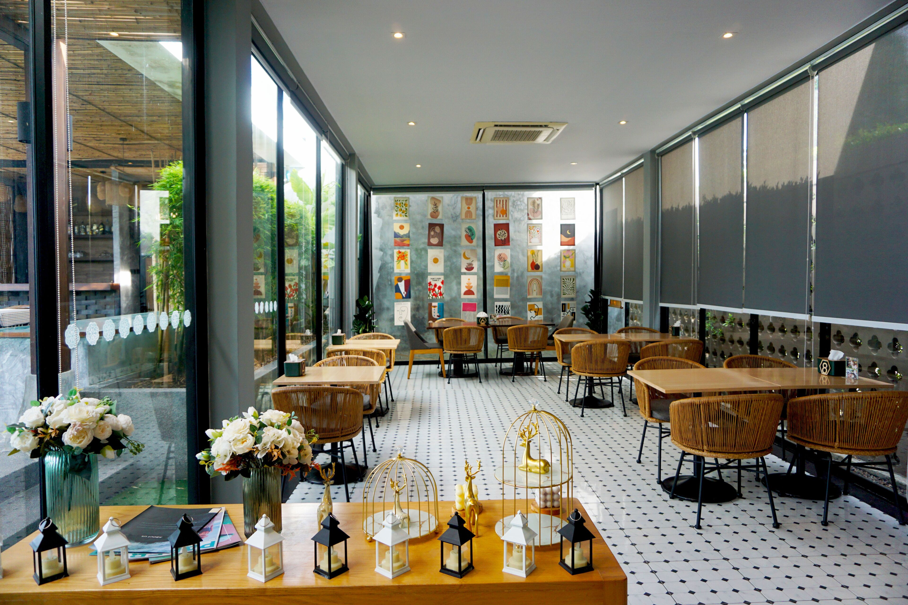 A restaurant with wooden tables and chairs, a patterned floor, and large windows with artwork.