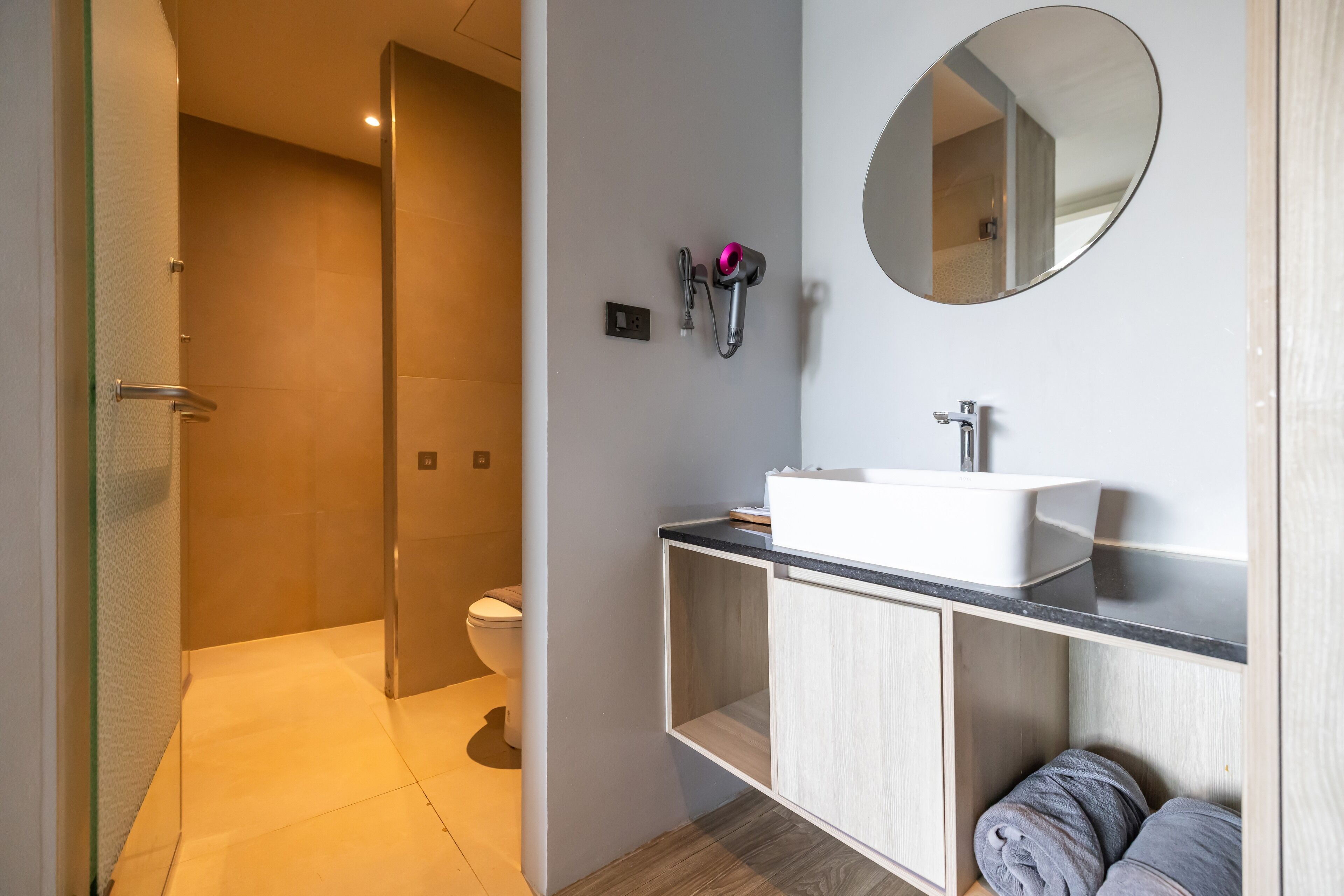 A modern bathroom with a glass-enclosed shower, a white sink, and a mirror.
