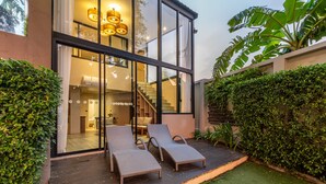 A modern house with large glass windows, a staircase, and two lounge chairs outside. - Antiya Hotel Phuket (Chalong)