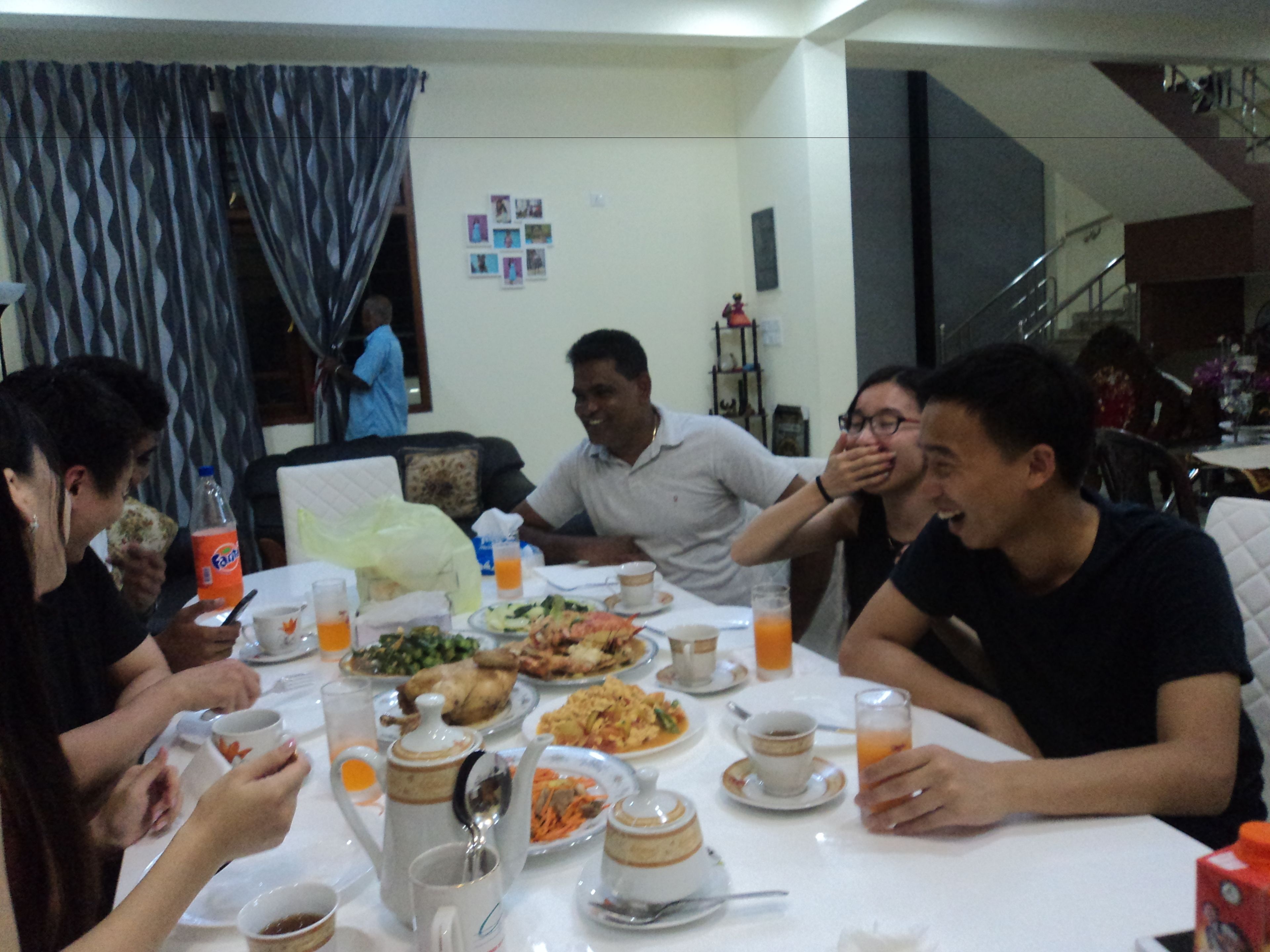 Un grupo de personas cenando en una mesa con varios platos, vasos y una botella de refresco.