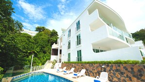 A modern hotel with a swimming pool, white exterior, and balconies. - Shanaya Residence Ocean View Kata (Karon)