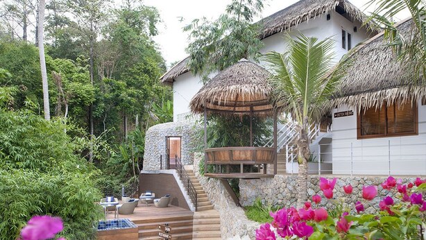 A resort with a stone staircase leading to a wooden deck, surrounded by lush greenery and a thatched-roof structure. - Shanaya Residence Ocean View Kata (Karon)