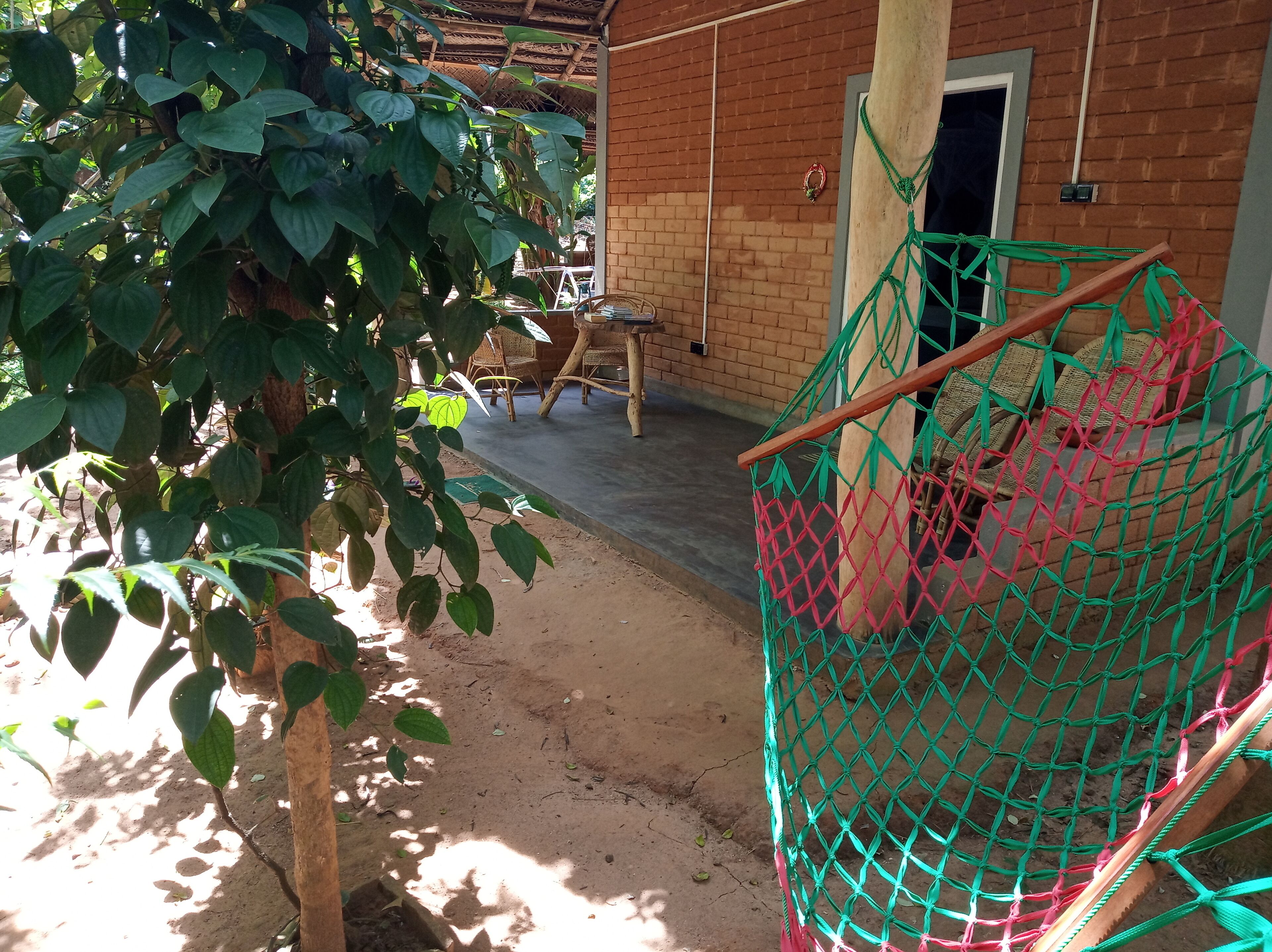 A covered outdoor area with a brick building, a wooden table, and chairs.