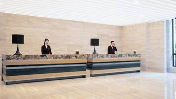 En receptionsdisk med två anställda, en vägg av marmor och en modern takdesign.