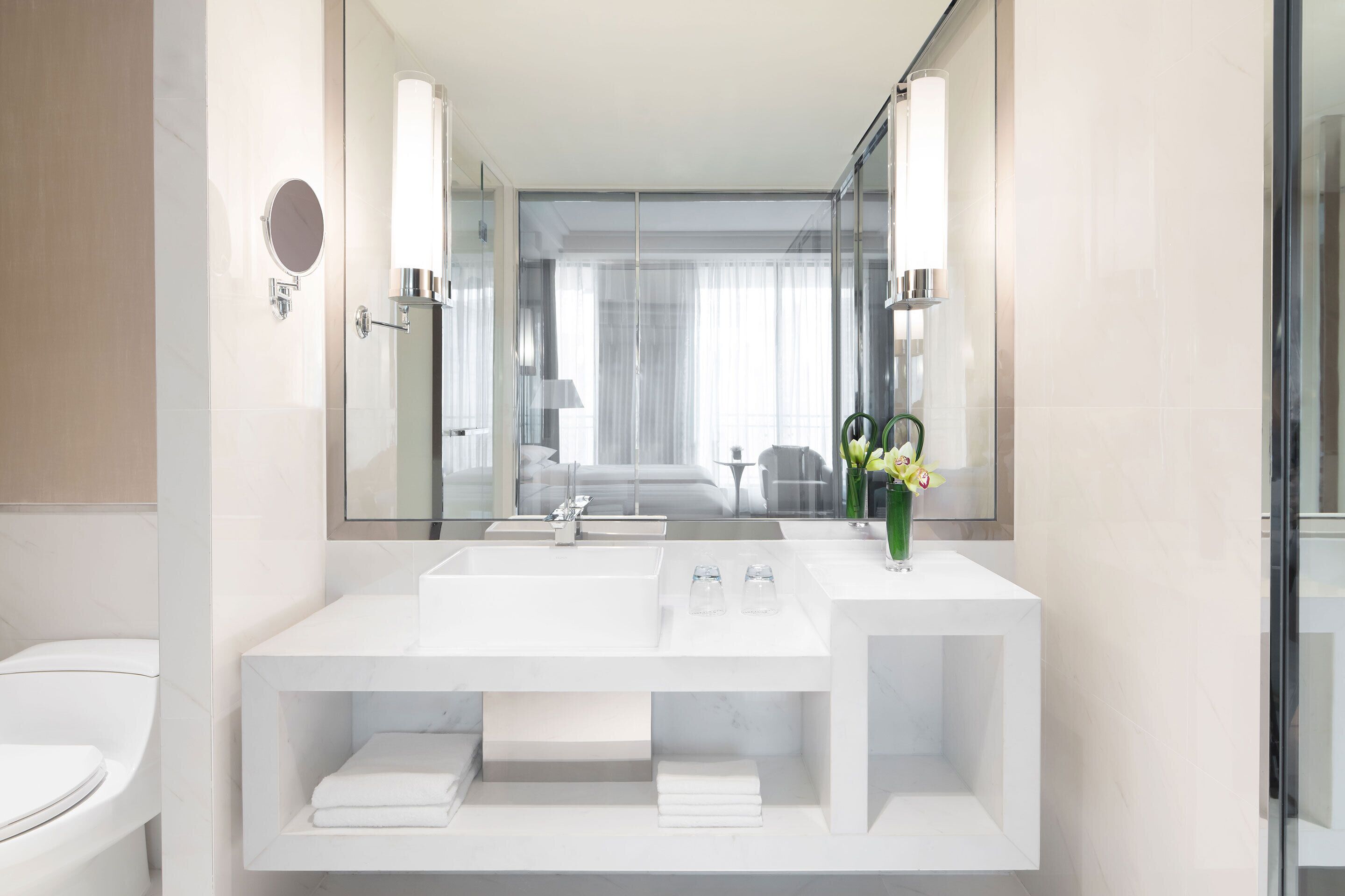 Ein modernes Badezimmer mit Waschbecken, Spiegel und Toilette in Weiß.